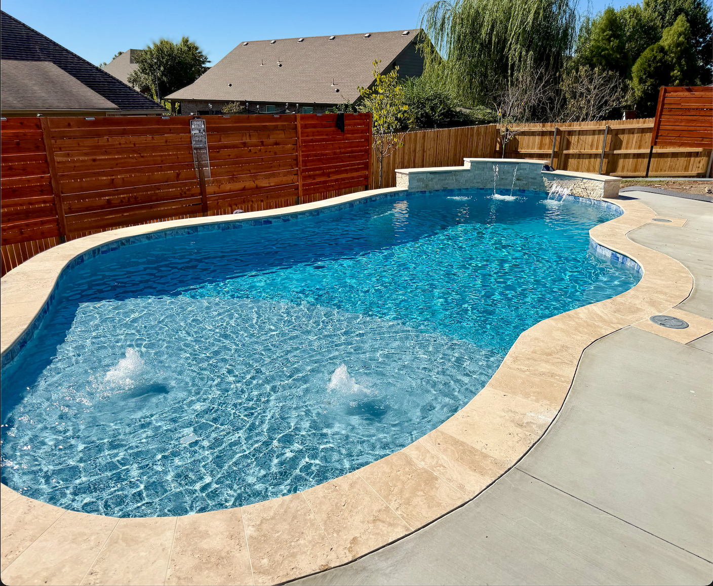 A rectangular pool filled with turquoise water, surrounded by concrete, set amidst a forest with bare trees.
