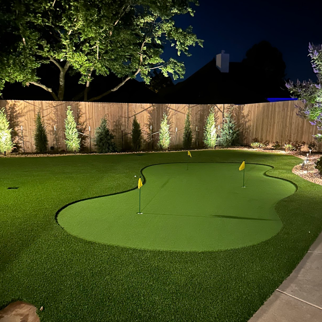 Aerial view of a park with playground equipment, green artificial turf, paths, trees, and a gazebo.