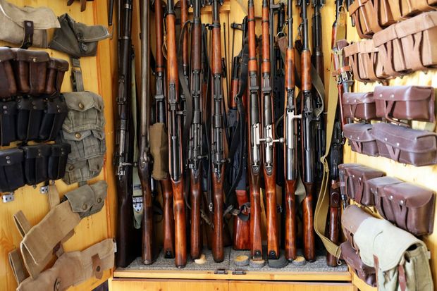 A cabinet filled with rifles and ammunition pouches; wooden interior.