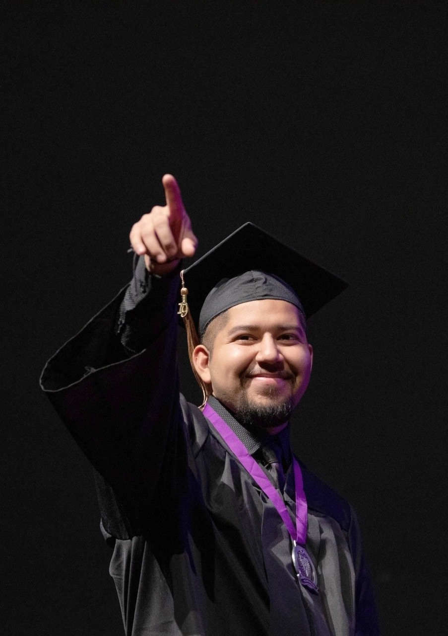 STUDENT IN CAP AND GOWN AT GRADUATION