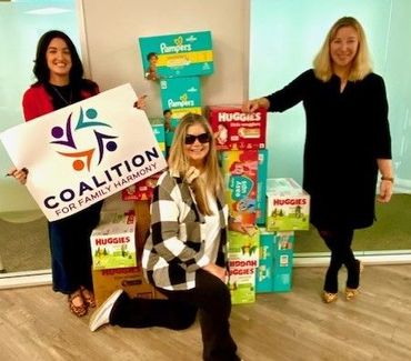 Three people pose with a sign reading