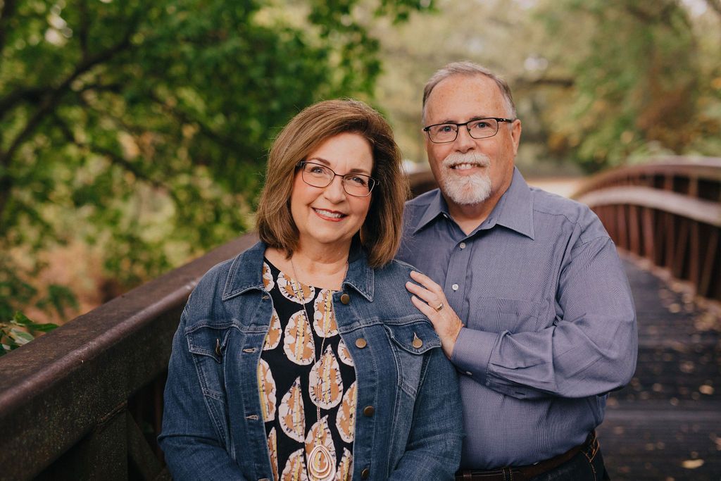 A man and a woman are posing for a picture on a bridge.