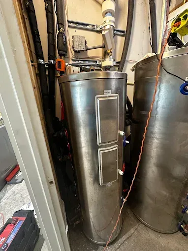 Stainless steel cylindrical tank in an industrial setting, with attached panels and piping.