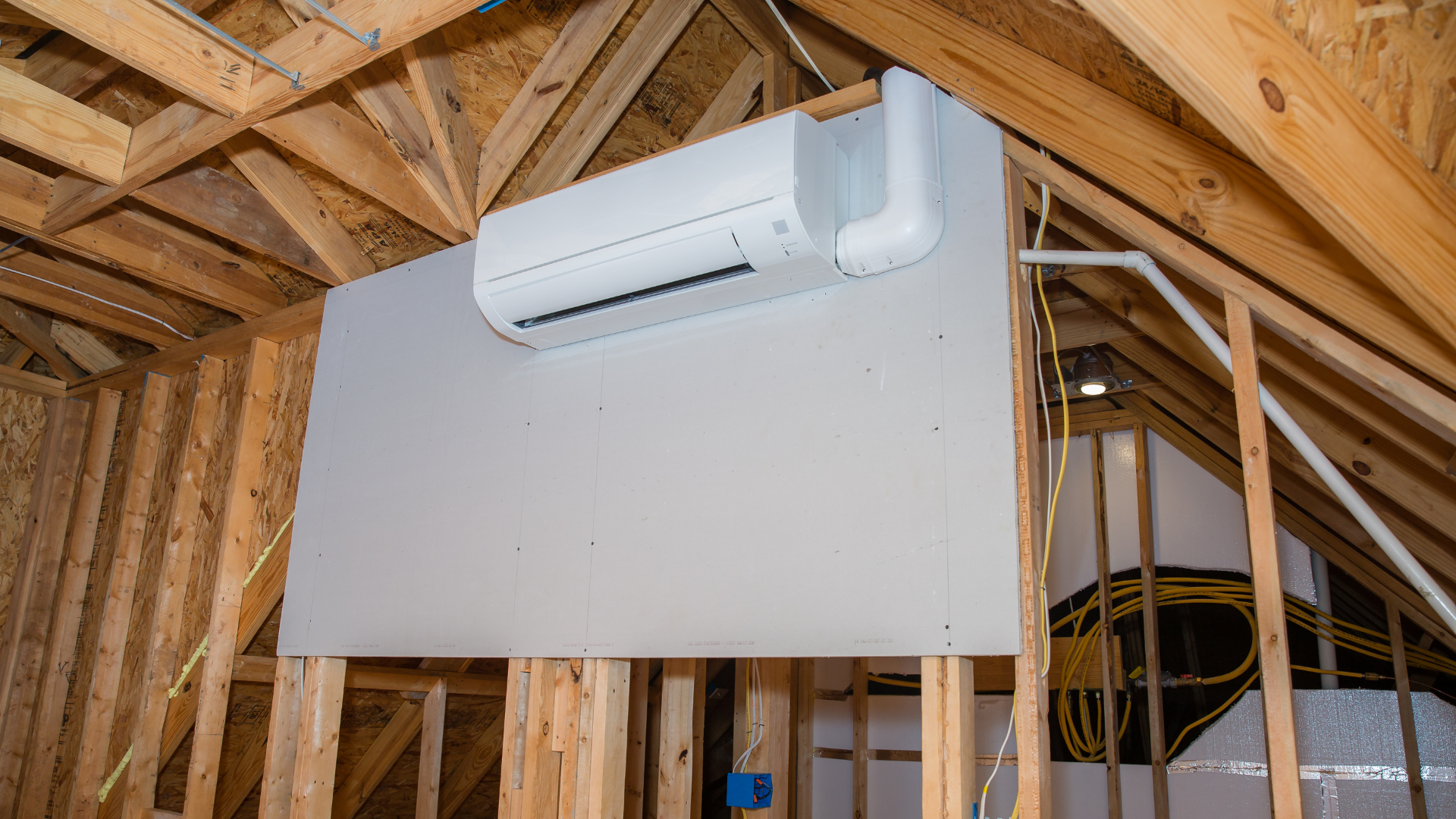 White air conditioning unit on a beige rooftop against a clear blue sky.