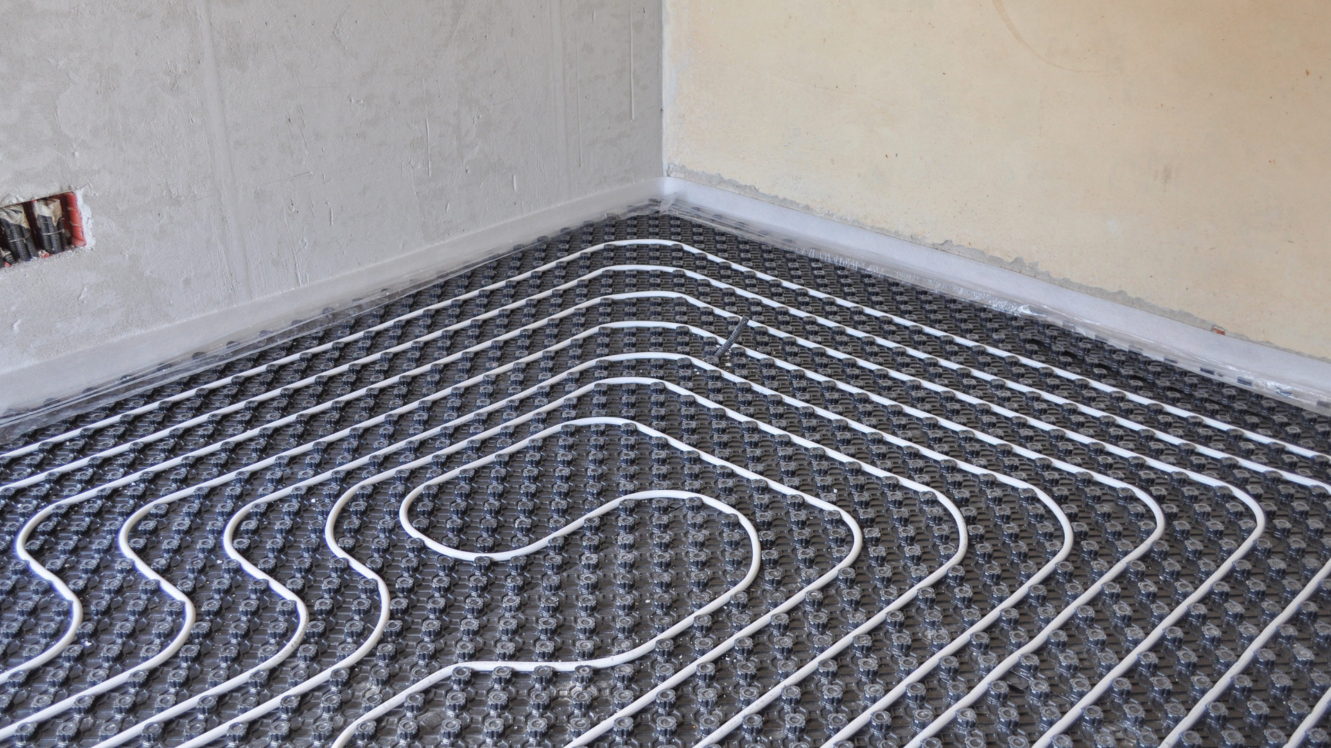 Four gray air conditioning units outside, with bushes and building siding.