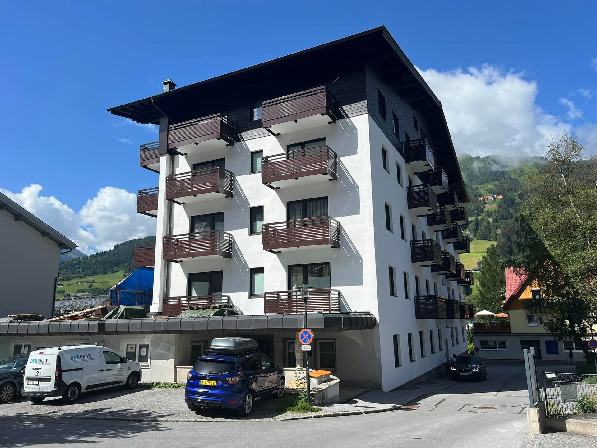 Ein großes weißes Gebäude mit Balkonen und davor geparkten Autos