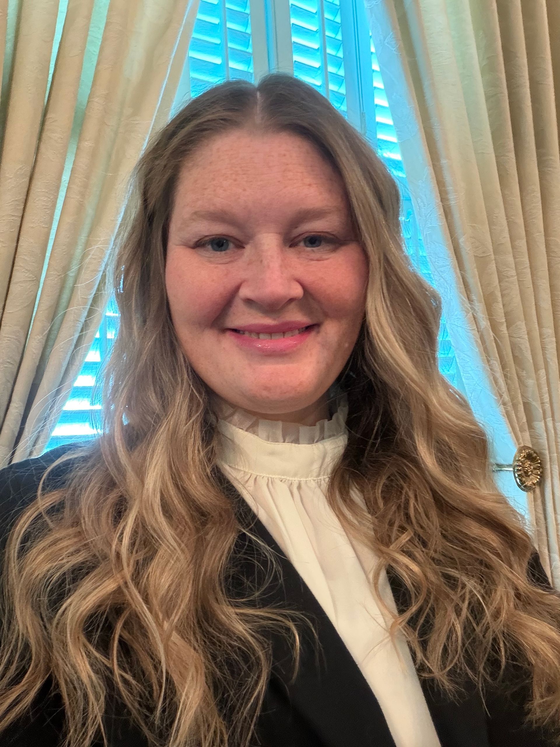 Man in a dark suit smiles, wearing a tie; light complexion, short gray hair.