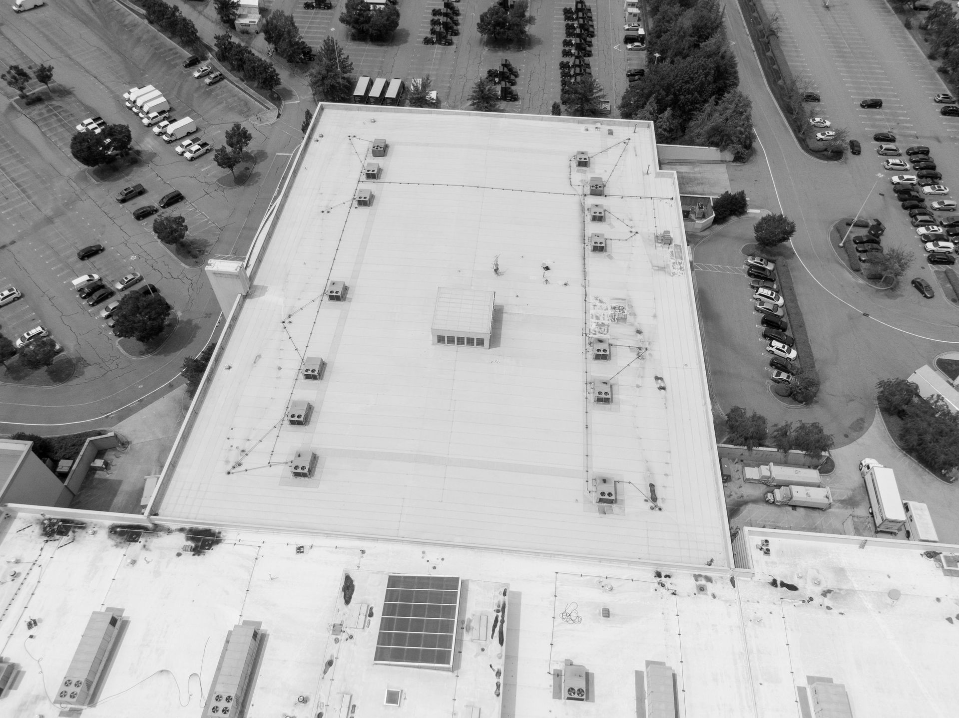 Une vue aérienne du toit d'un grand immeuble avec un parking en arrière-plan.