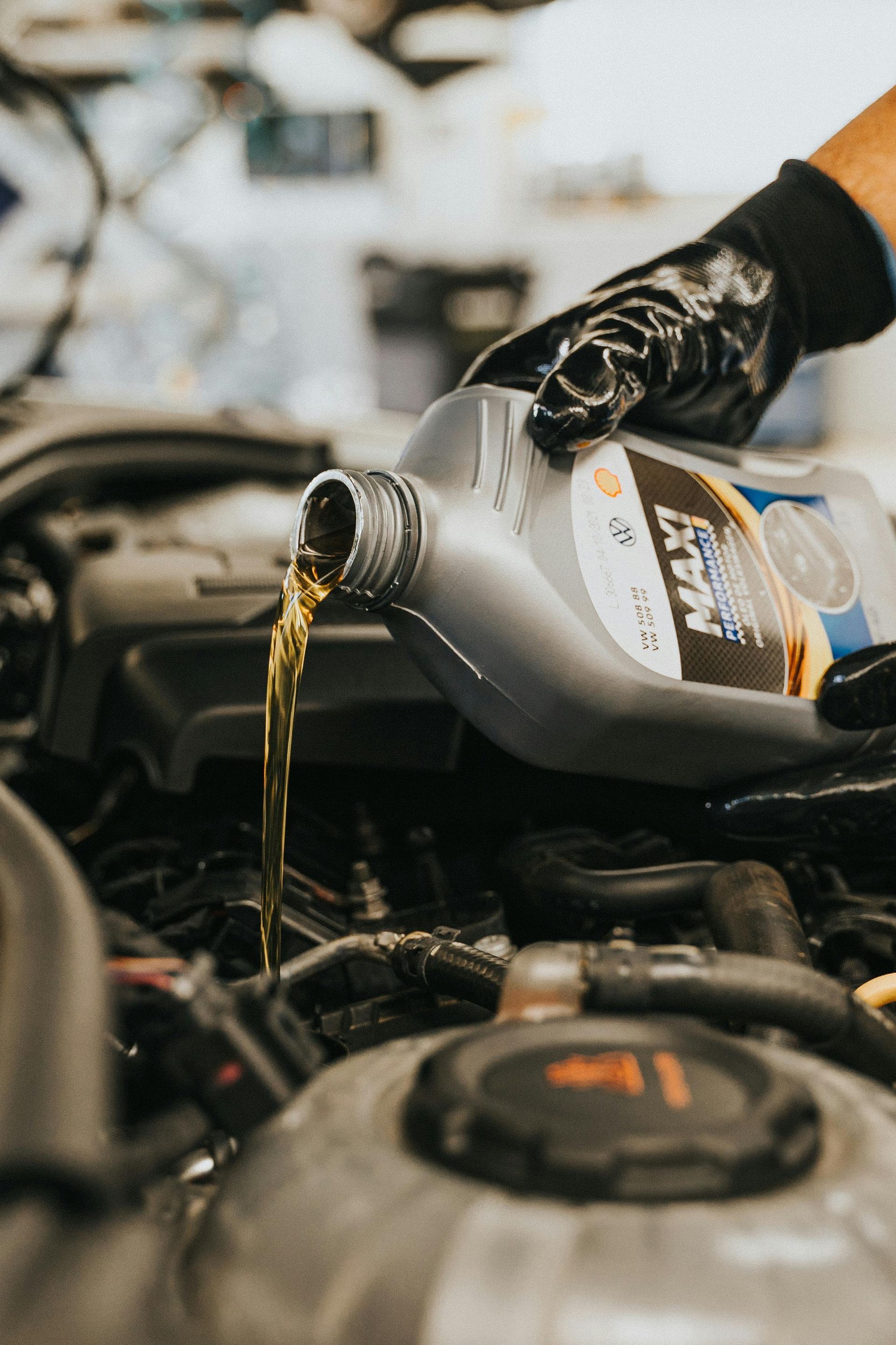 A person is pouring oil into a car engine.