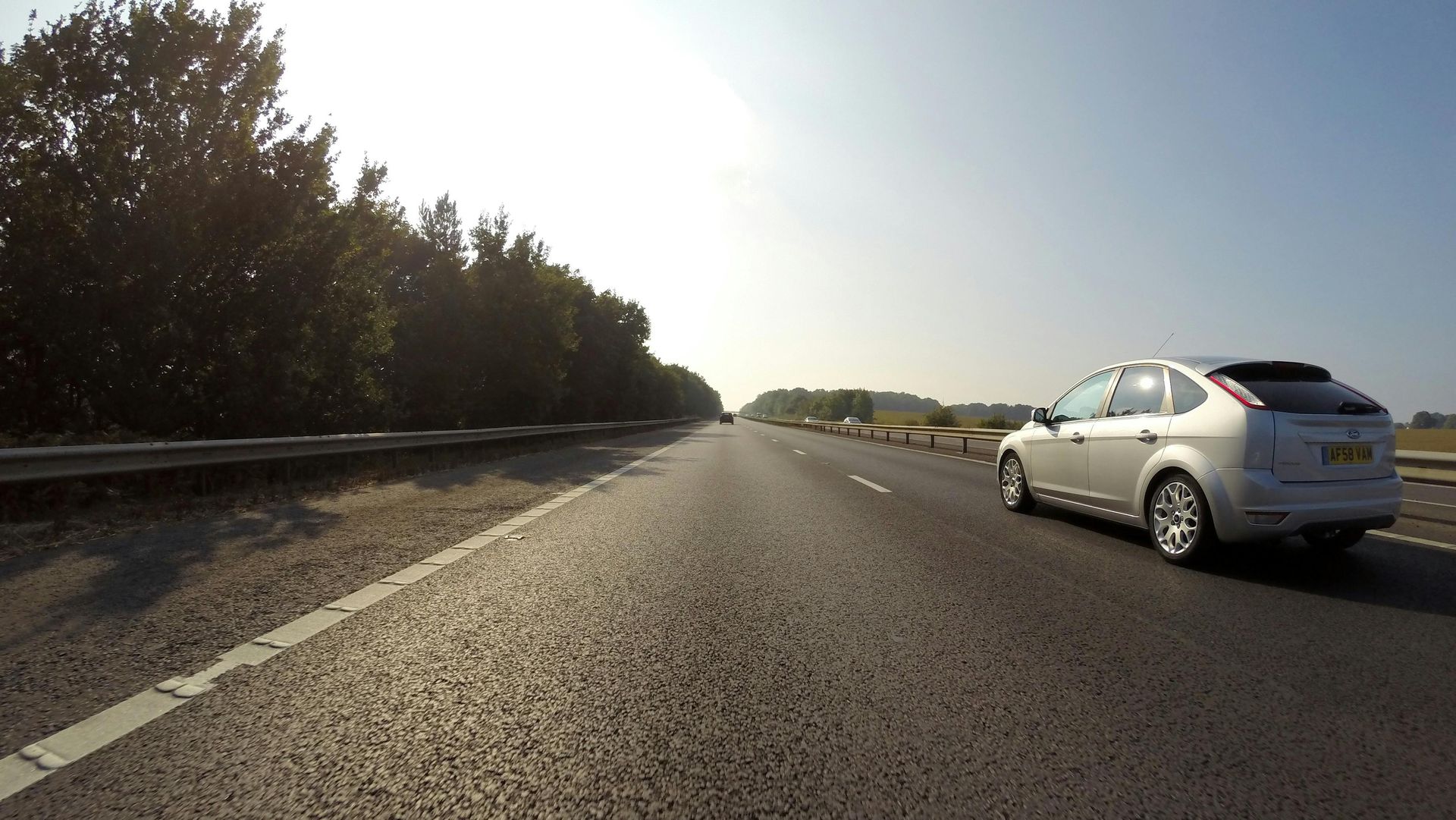 A white car is driving down an empty highway