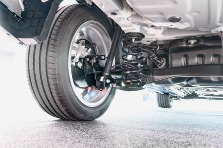 A close up of the underside of a car with a tire and shock absorber.