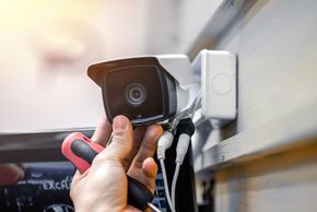 A man installing a security camera on a wall. A man installing a security camera on a wall.
