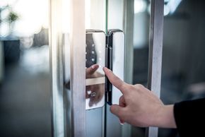 Woman using a keypad lock on a glass door. Woman using a keypad lock on a glass door.