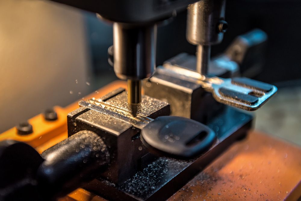 A professional locksmith machine makes an auto key duplicate.