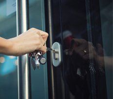 A man unlocking a glass door of an office with a key. A man unlocking a glass door of an office with a key.