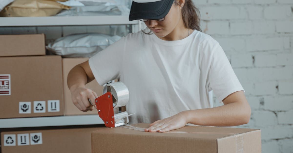 A woman is taping a cardboard box with tape.