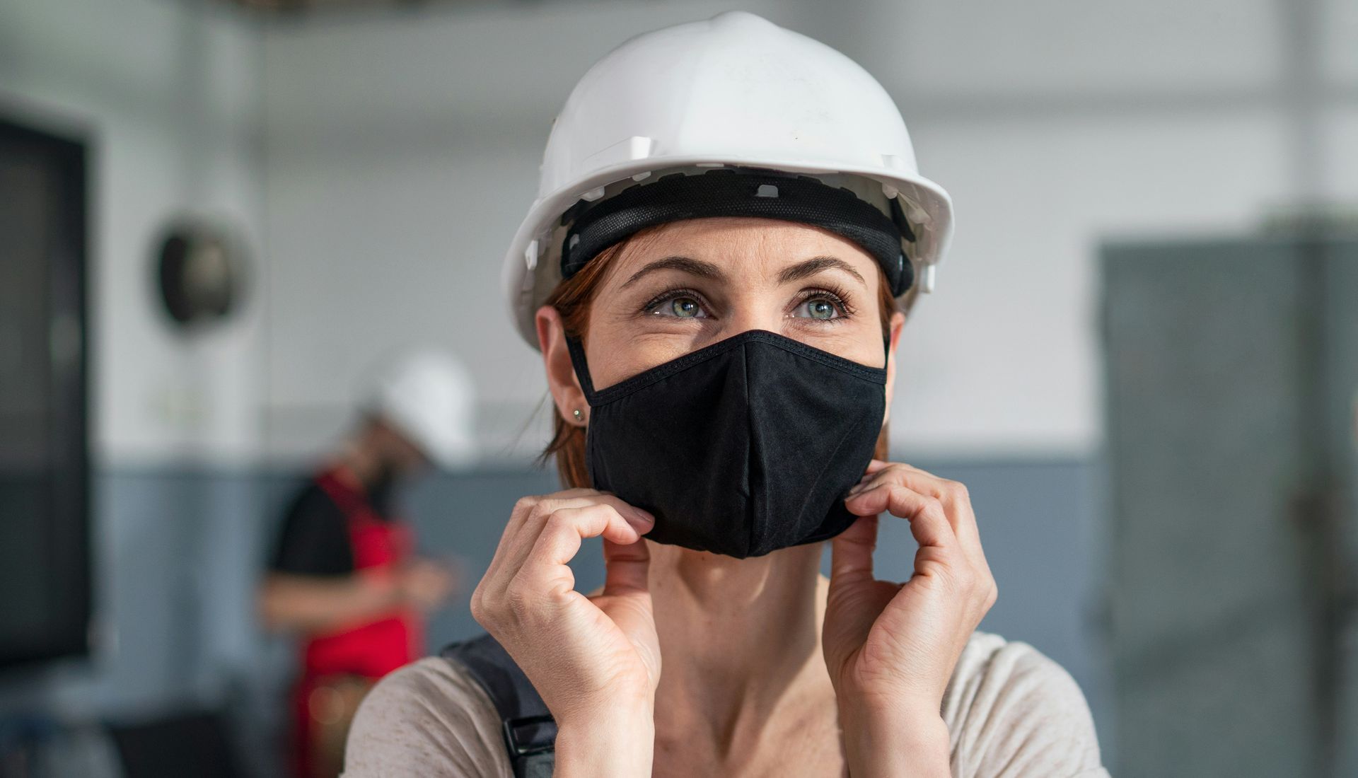 A woman wearing a hard hat and a face mask.