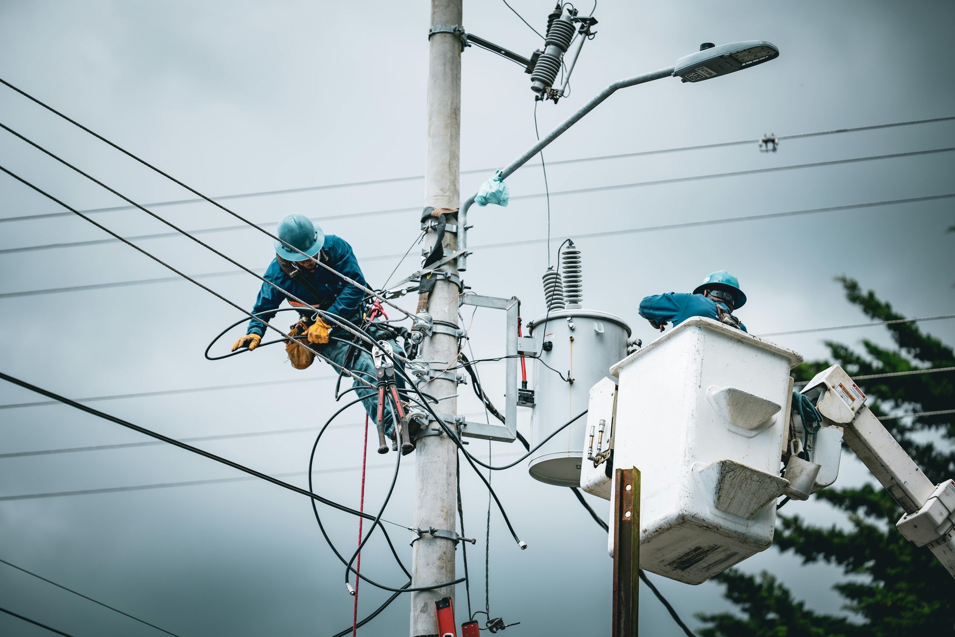 A man is working on a power pole with a bucket.