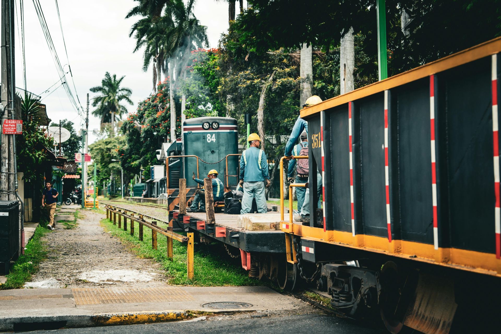 A train is going down the tracks next to a road.