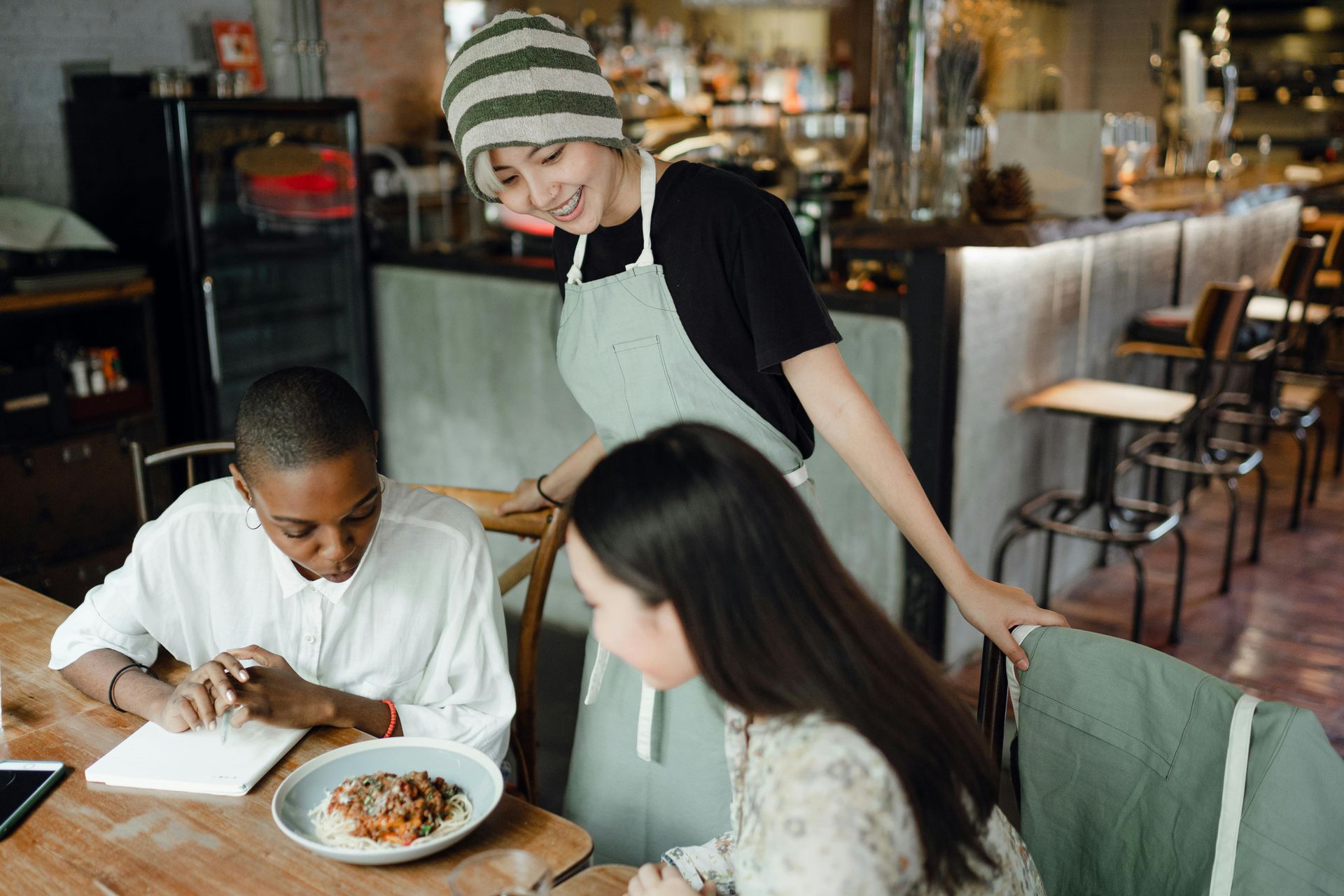 A woman is serving food to two people in a restaurant.