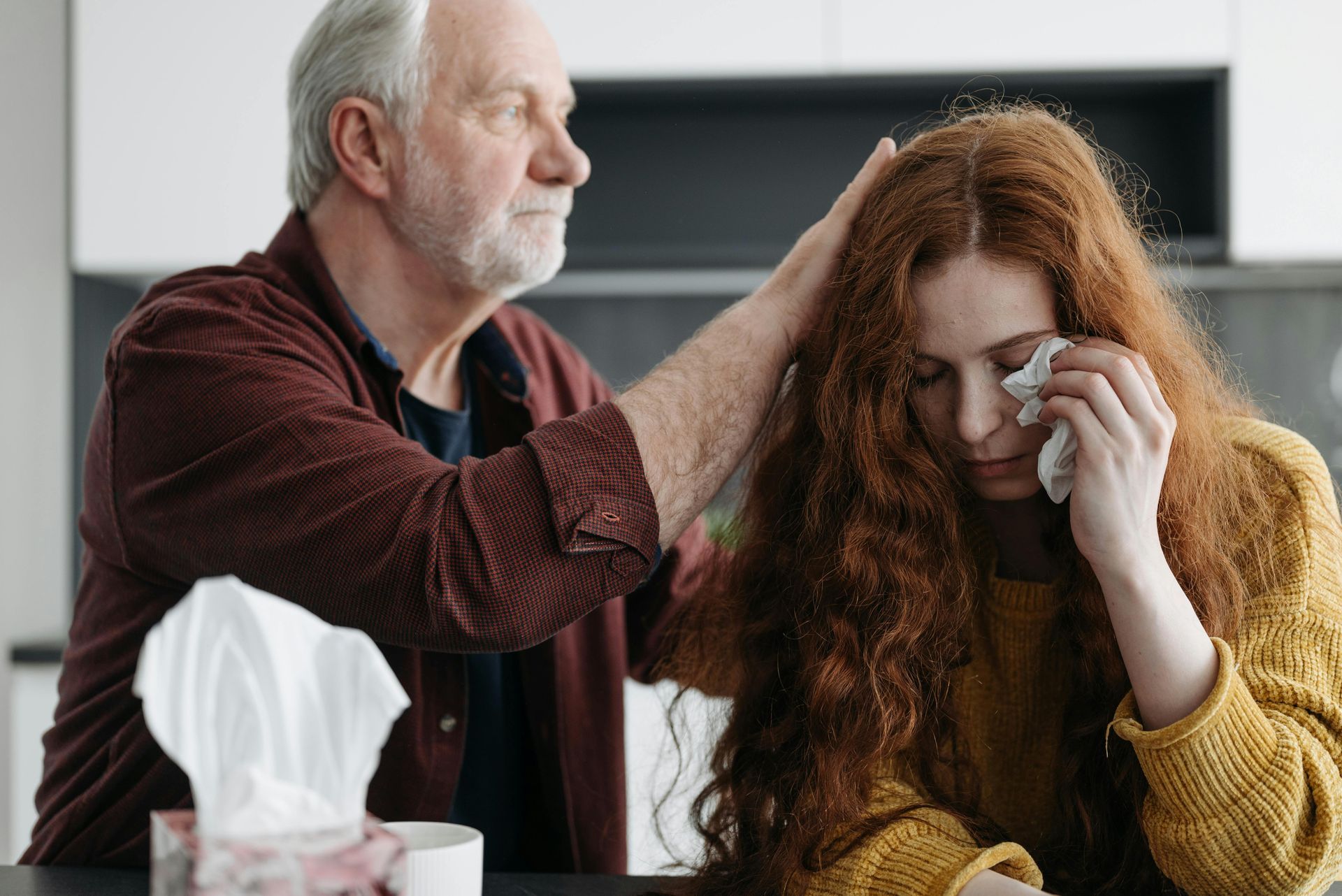 A man is comforting a woman who is crying while sitting at a table.