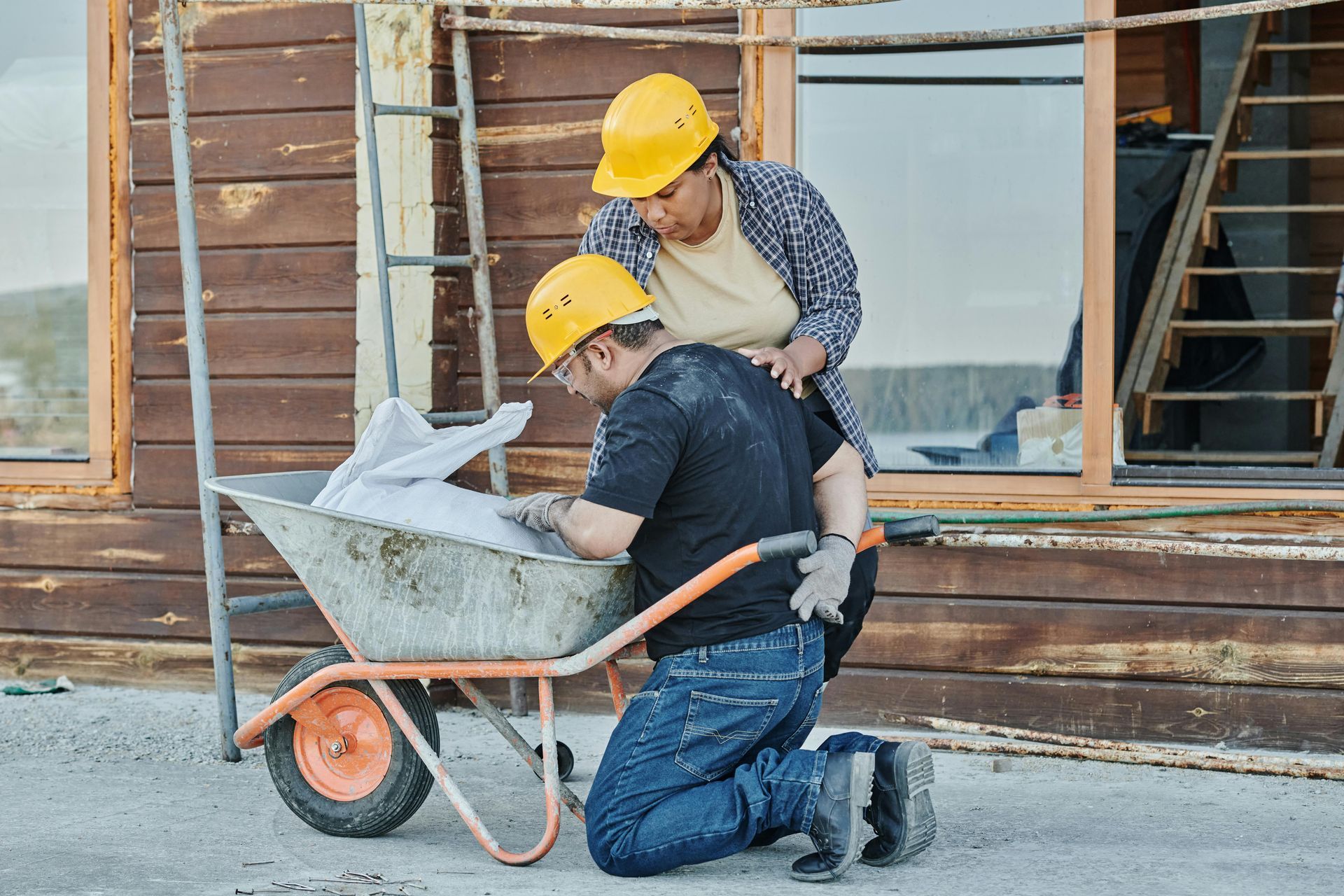 A man is pushing a wheelbarrow with a cat in it.