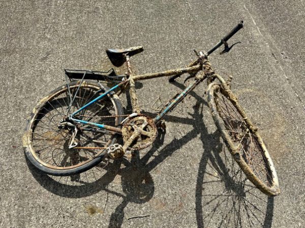 A dirty bicycle is laying on the ground.