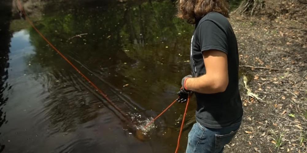 A man is fishing in a river with a rope.