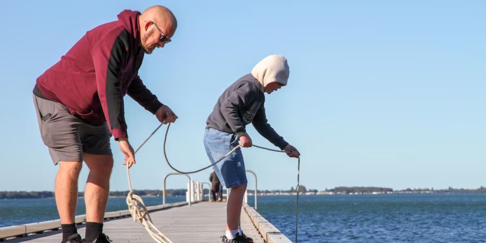 A man and a boy are fishing on a dock.