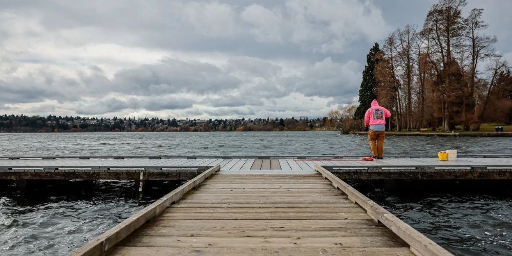 A person is standing on a wooden dock overlooking a lake.