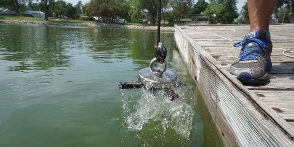 A person is standing on a dock next to a body of water.