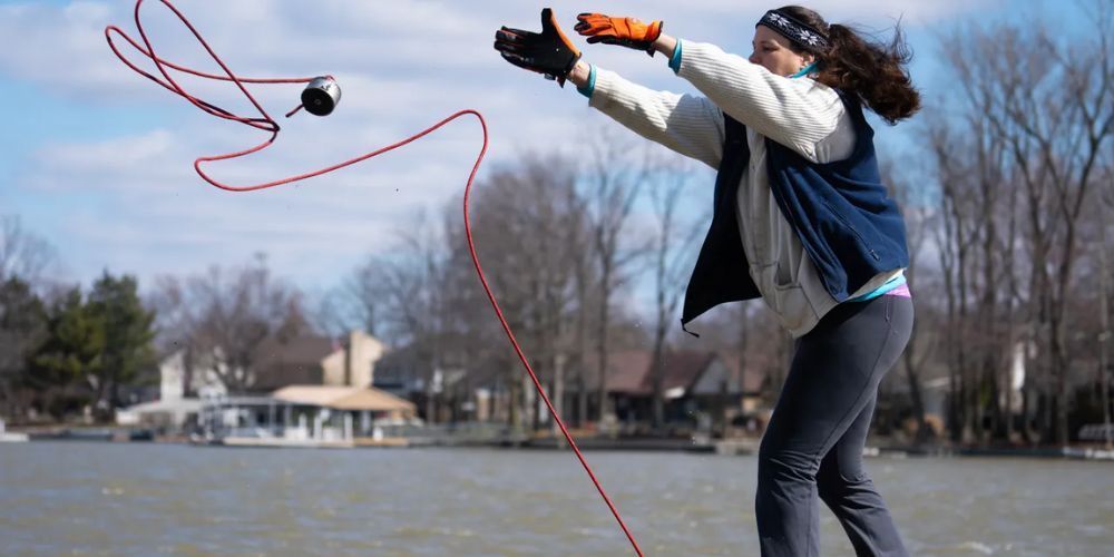 Woman throwing a water ski rope into a lake.