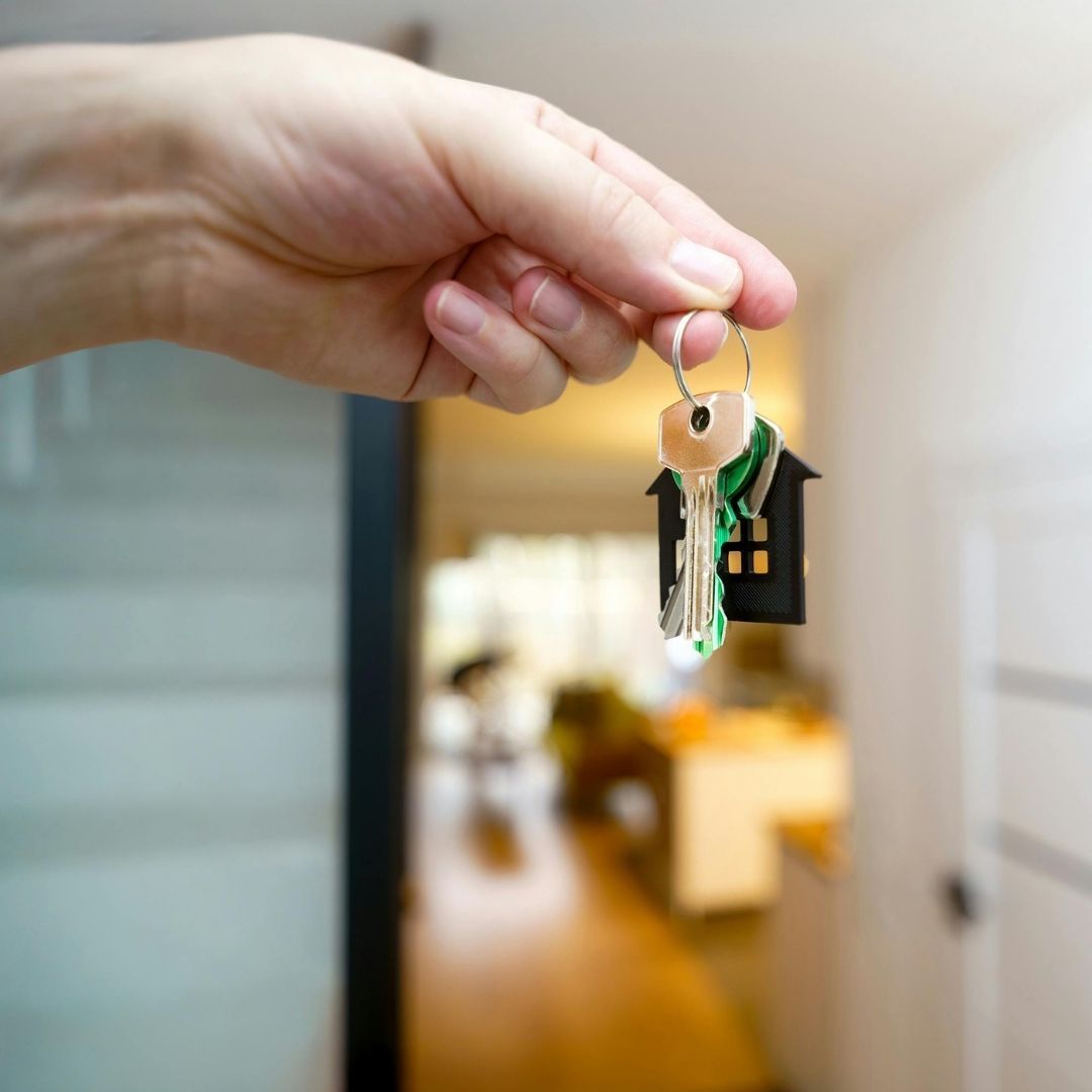 holding house keys in front of door of new home