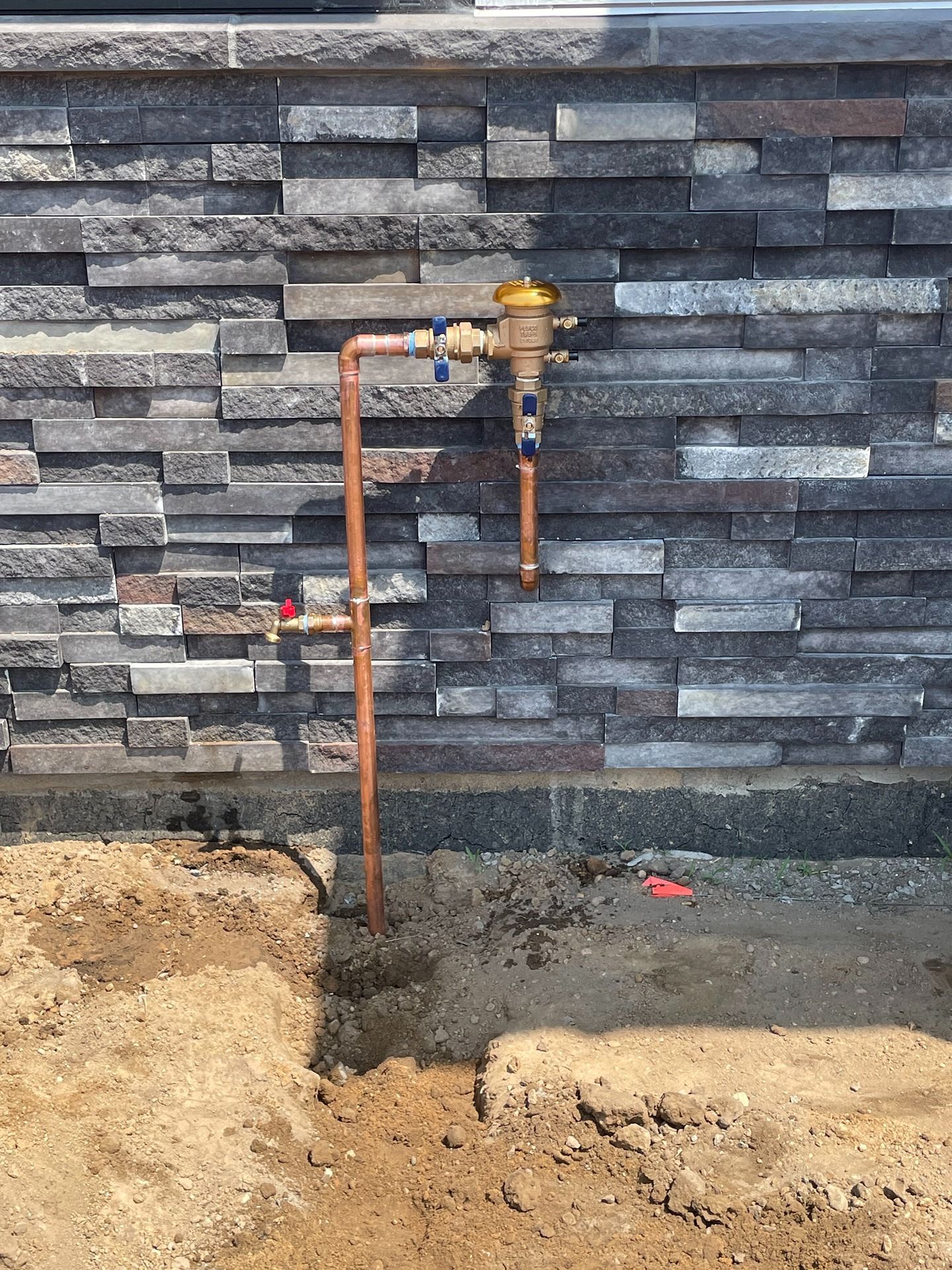 Woman in straw hat smiles, holding wine glass near a lake.