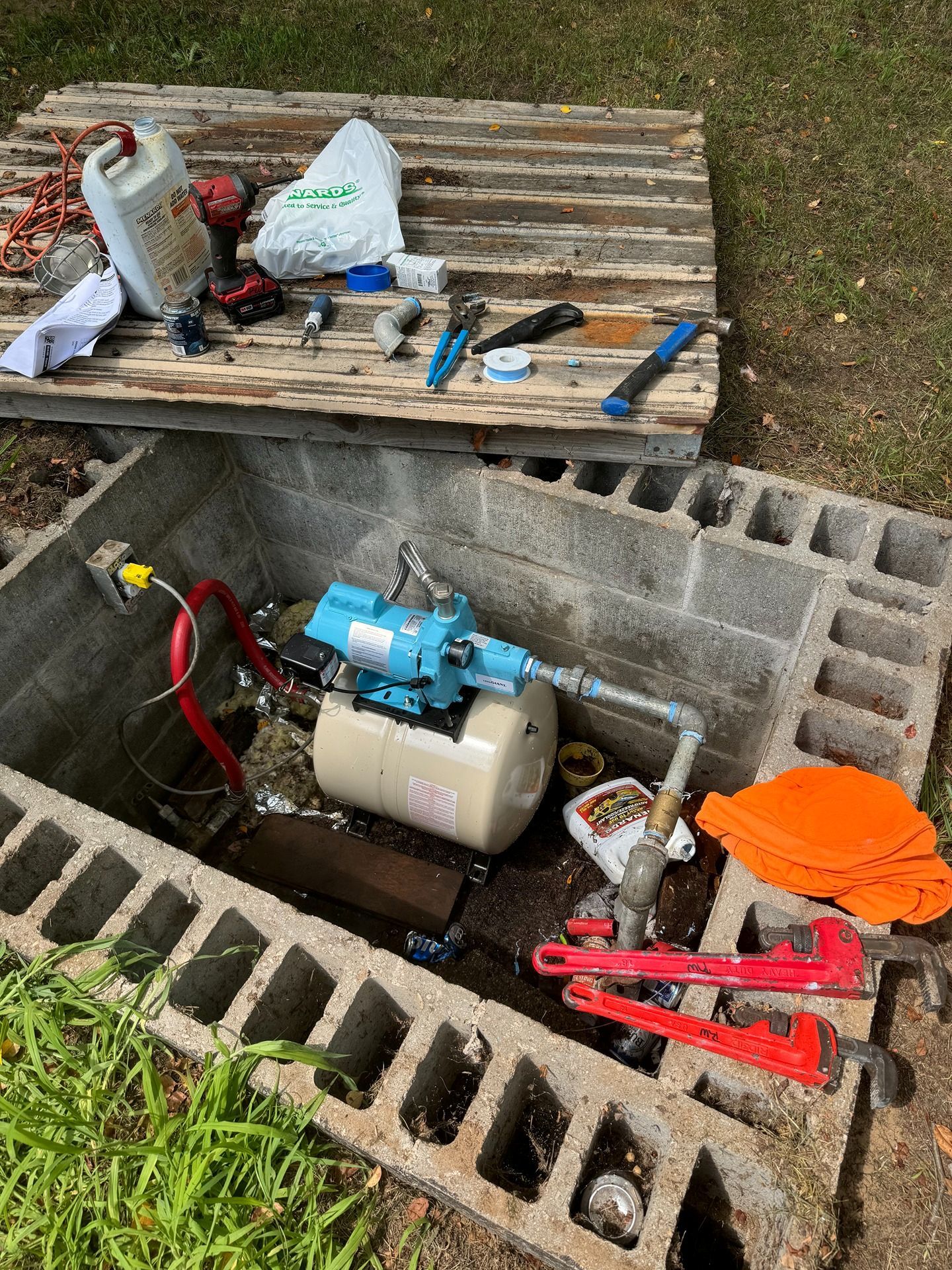 Woman in straw hat smiles, holding wine glass near a lake.