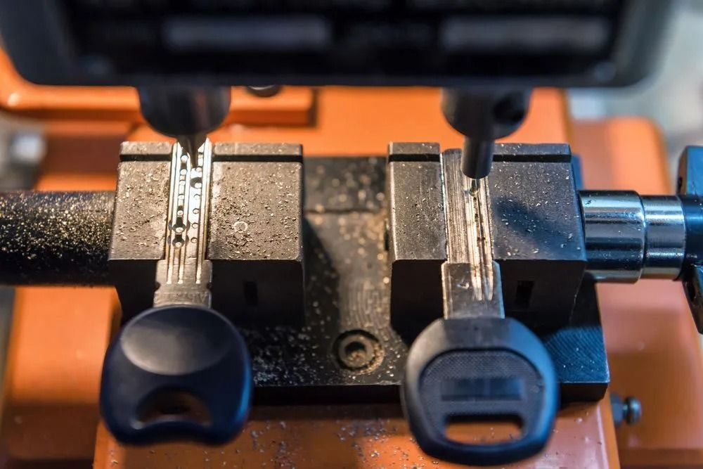 Key-cutting machine in action; two keys are being duplicated, with metal shavings present.