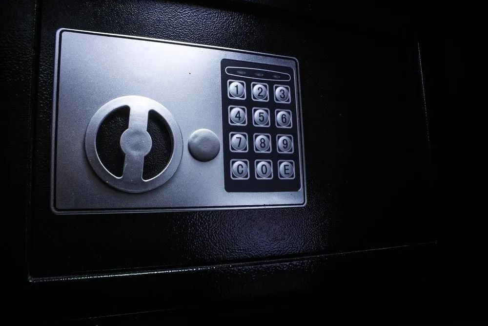 Close-up of a black safe with a digital keypad and a dial.