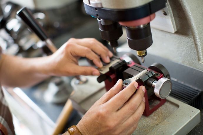 Hands using a key-cutting machine to make a new key.