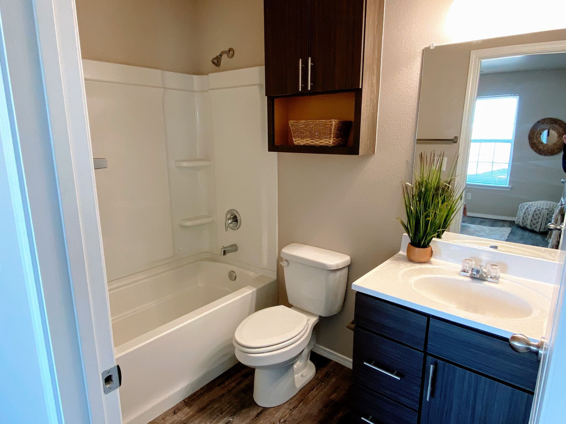 Bathroom with white tub/shower, dark wood vanity, and dark brown wall cabinet.