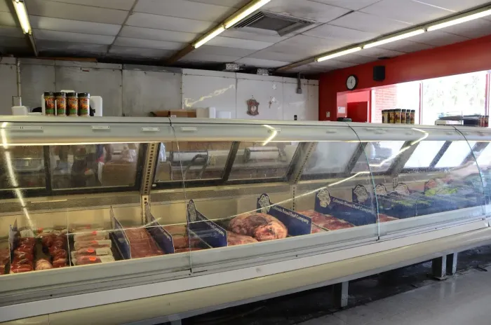 Butcher shop display case with assorted meats in a long refrigerated counter