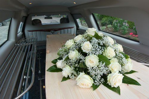 carro funebre con bara e fiori bianchi