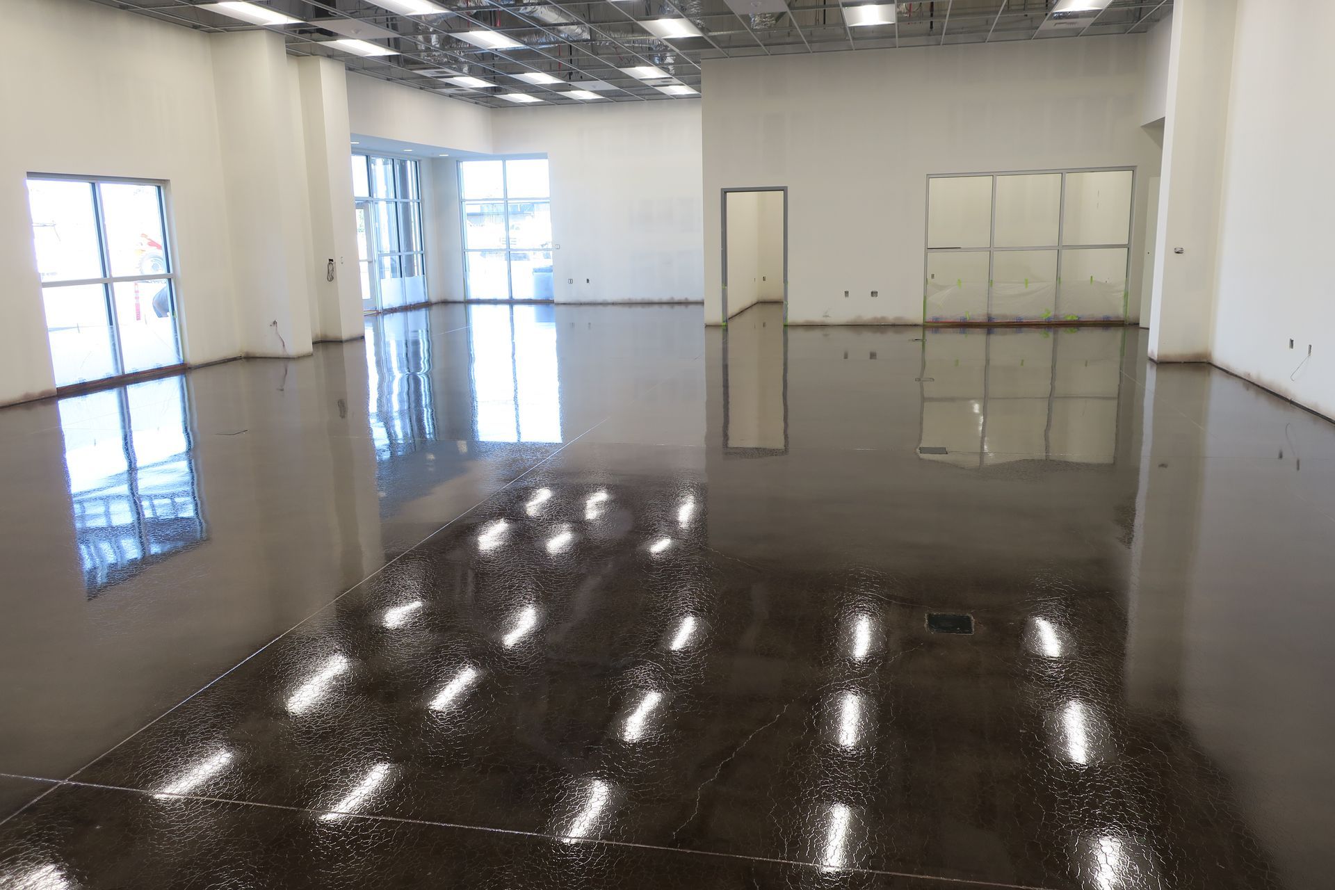 A large empty room with a shiny floor and lots of windows.