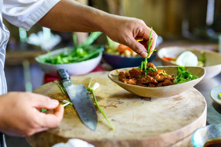 A person is preparing food on a wooden cutting board.