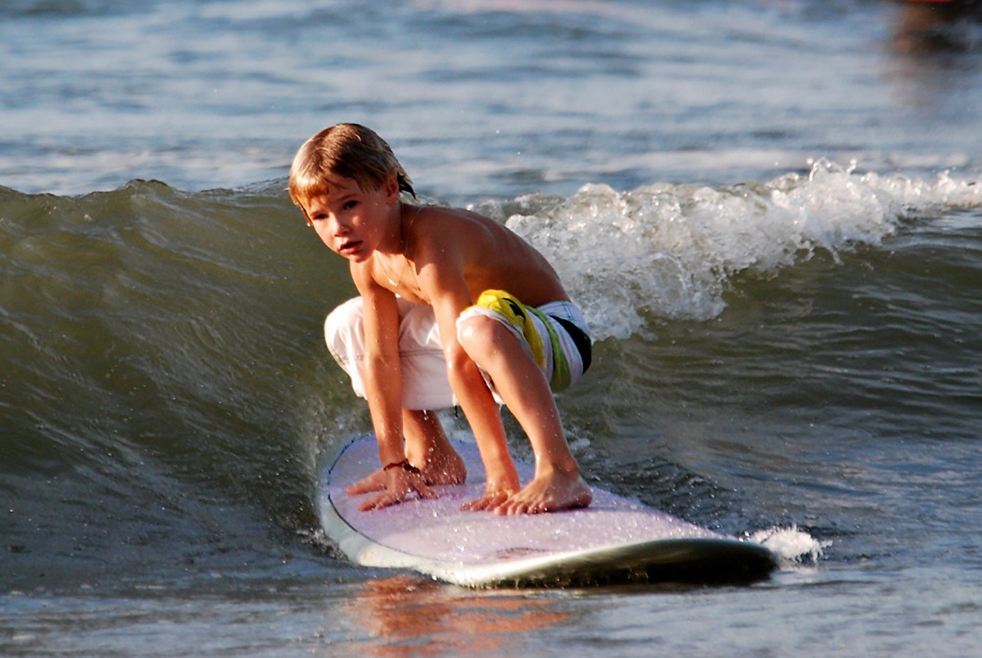 A young boy is riding a wave on a surfboard