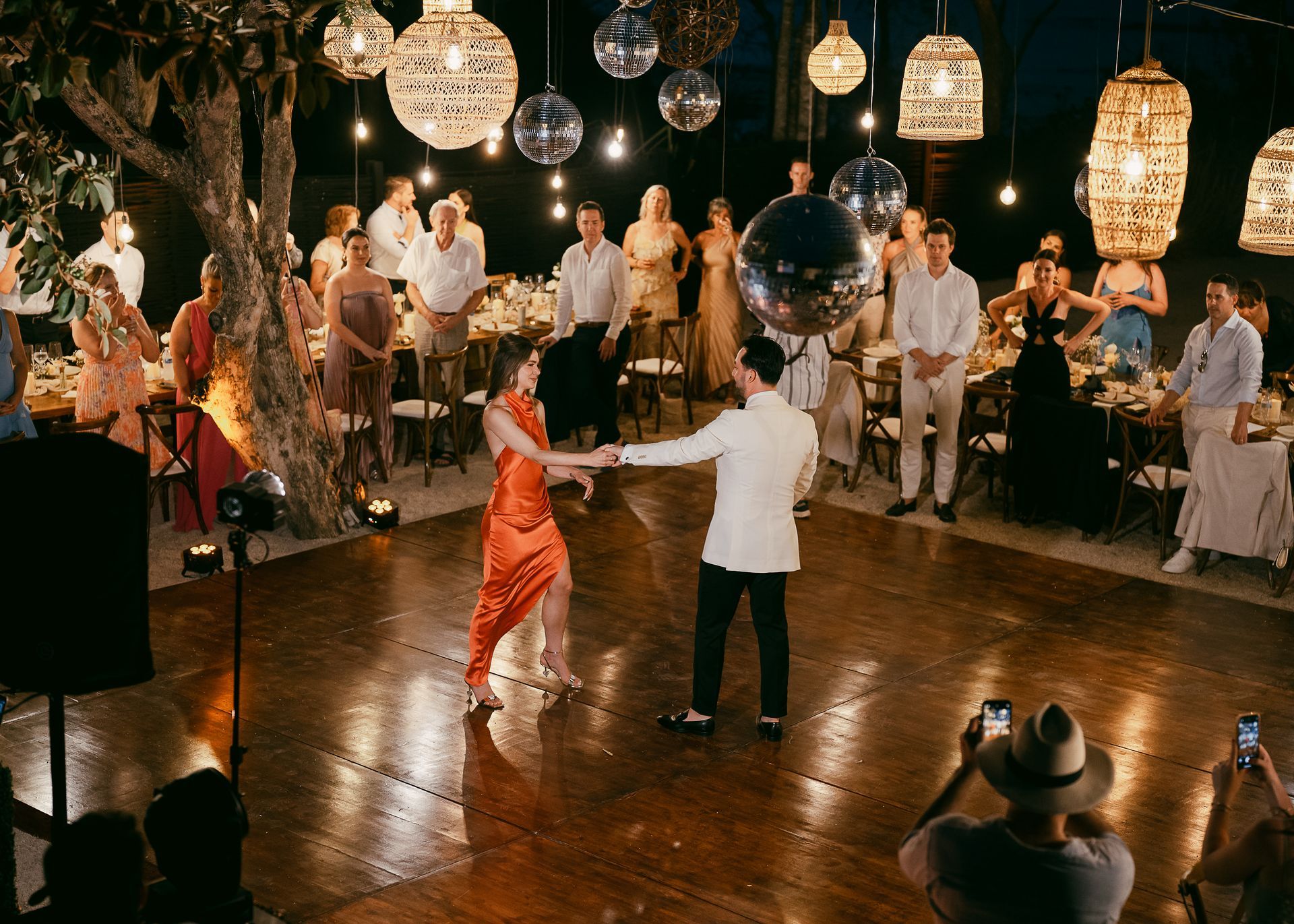 A man is taking a picture of a bride and groom dancing at a wedding reception.