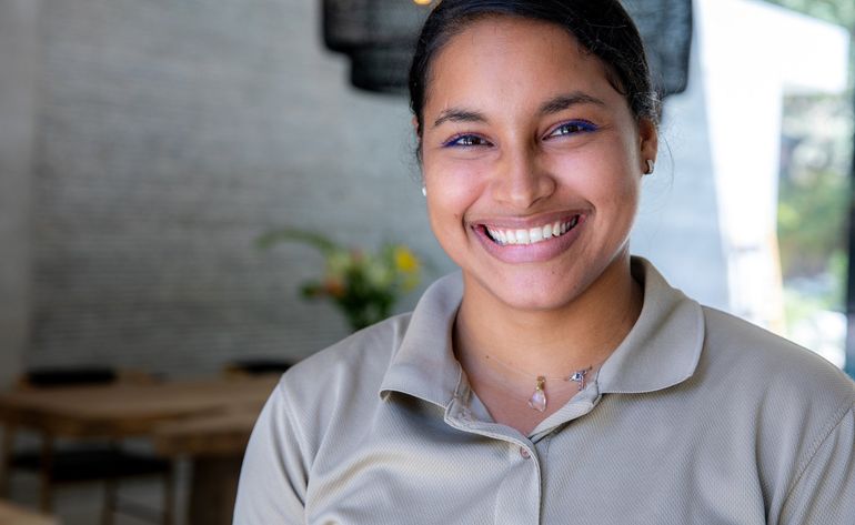 A woman is smiling for the camera in a restaurant.