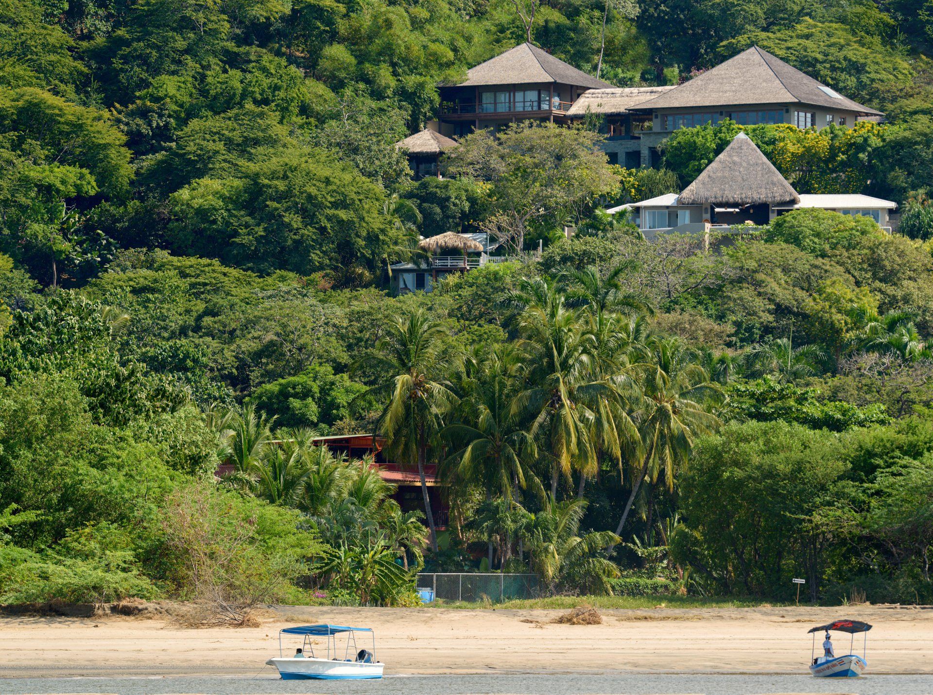 A large house sits on top of a hill surrounded by trees