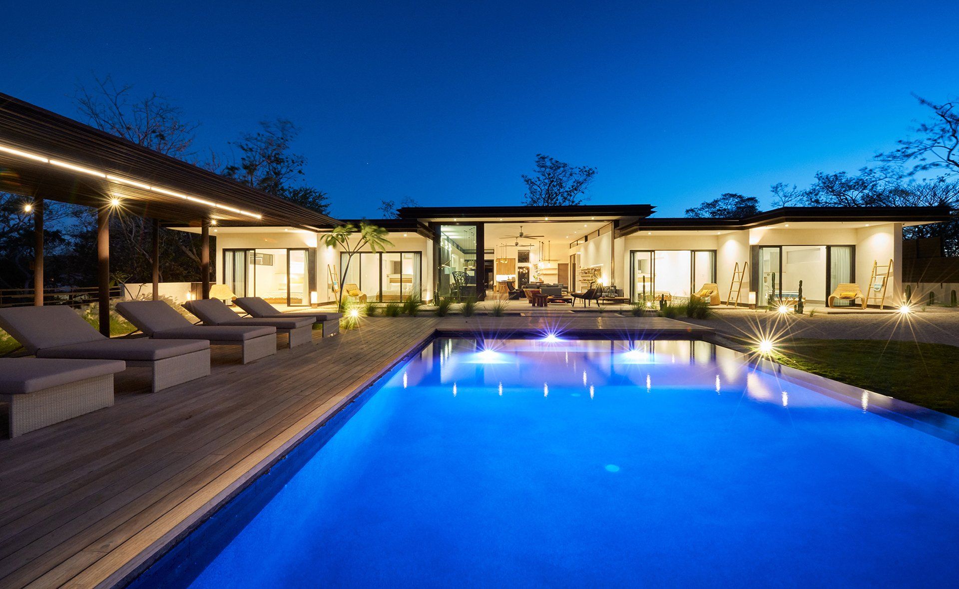 A large swimming pool in front of a house at night