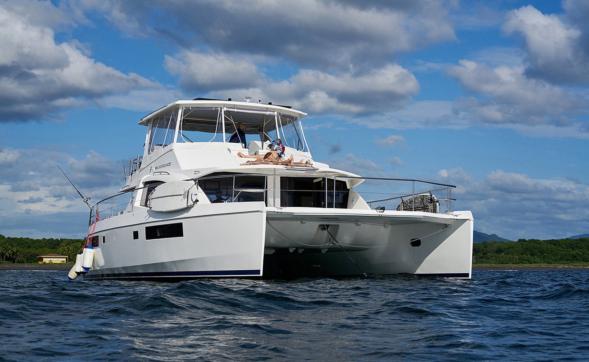 A white catamaran is floating on top of a body of water.