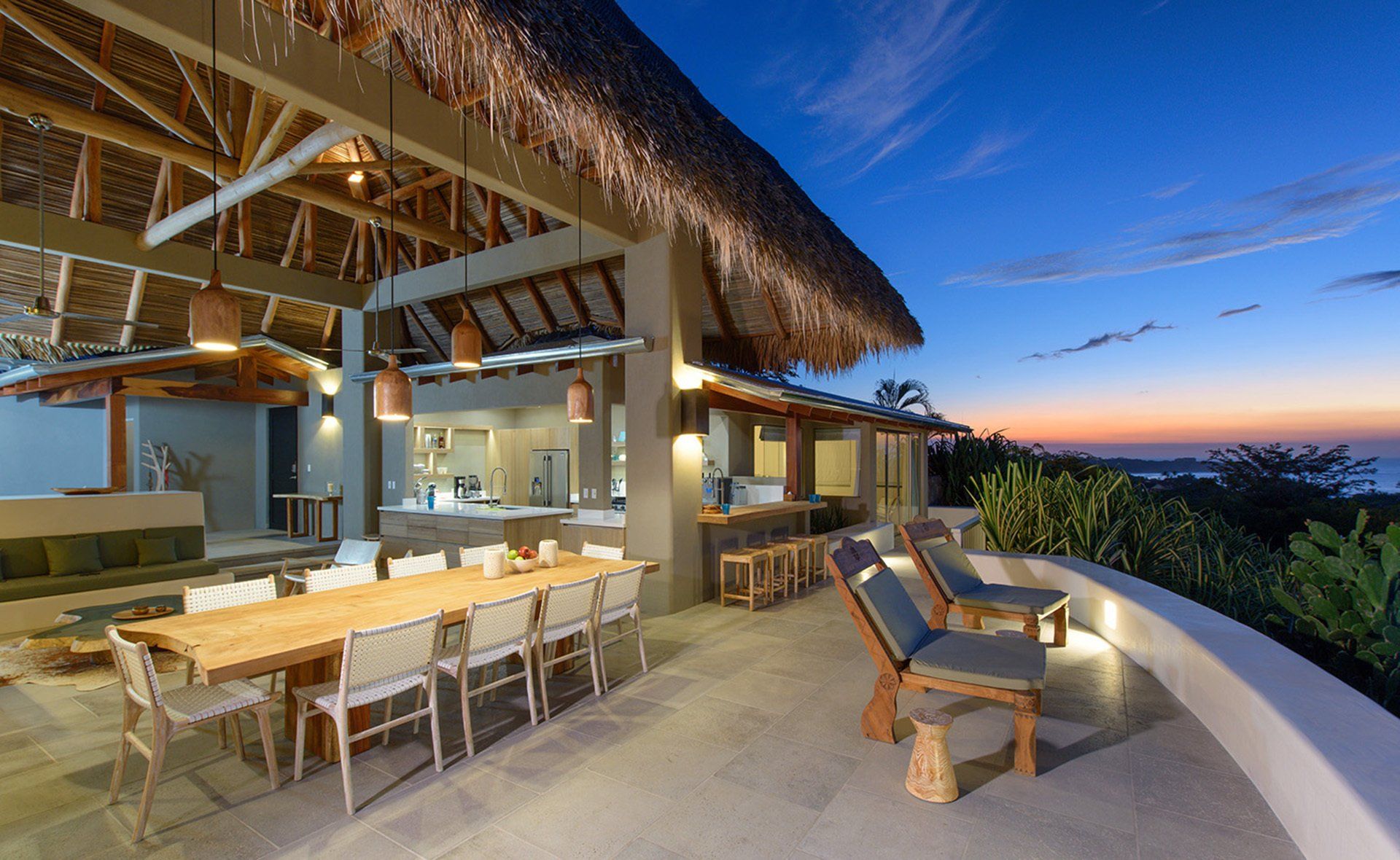 A large patio with a table and chairs and a thatched roof.